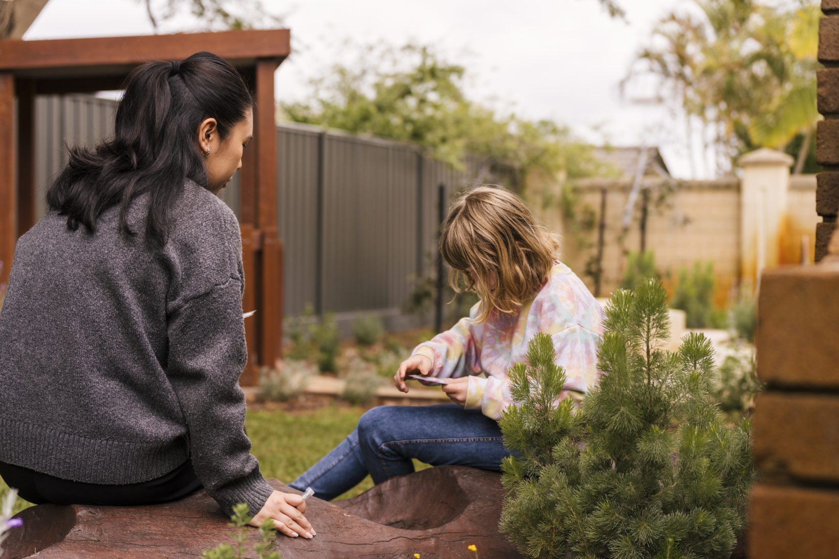 Young girl and Occupational Therapist talking quietly in the calm sensory garden of Kids Are Kids! at 16 Clarence Road, Armadale